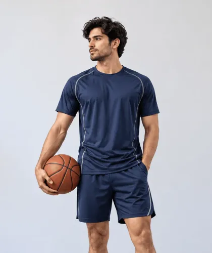 A man in a navy performance tee and matching shorts with contrast piping, holding a basketball.