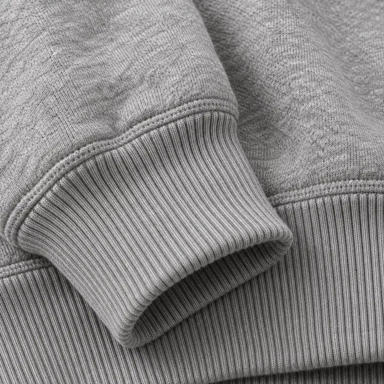 Close-up of a ribbed cuff resting on the ribbed hem of a grey hoodie.