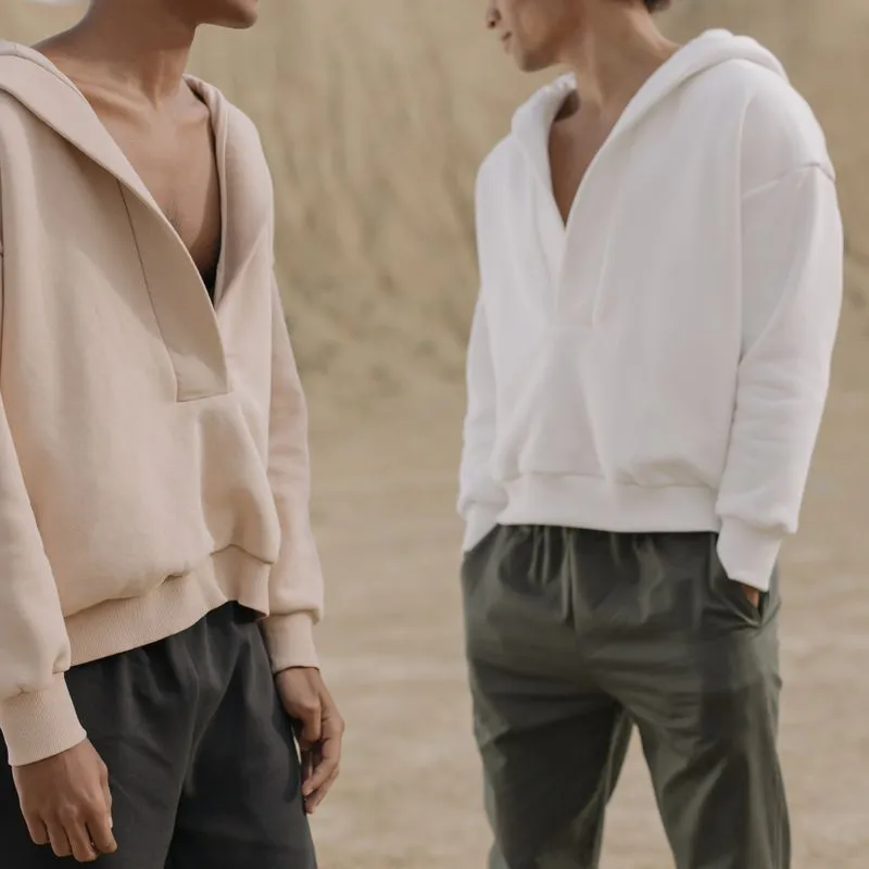 Two models in cropped, dropped-shoulder V-neck pullover hoodies, one tan and one white.