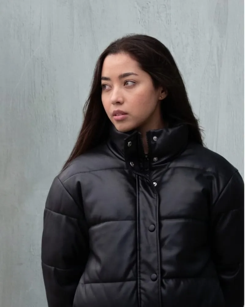 A model in a black faux-leather puffer jacket with a quilted baffle pattern and snap placket.