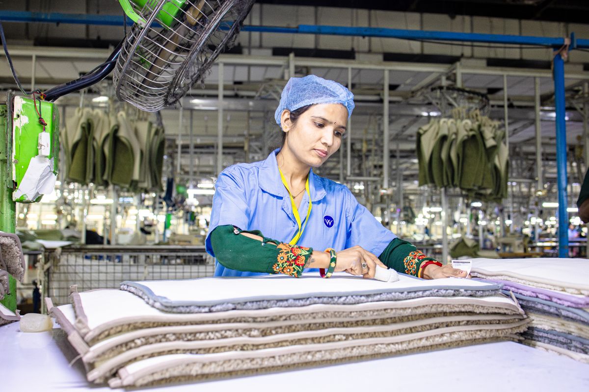 A worker inspecting stitching and fabric at a quality checkpoint.
