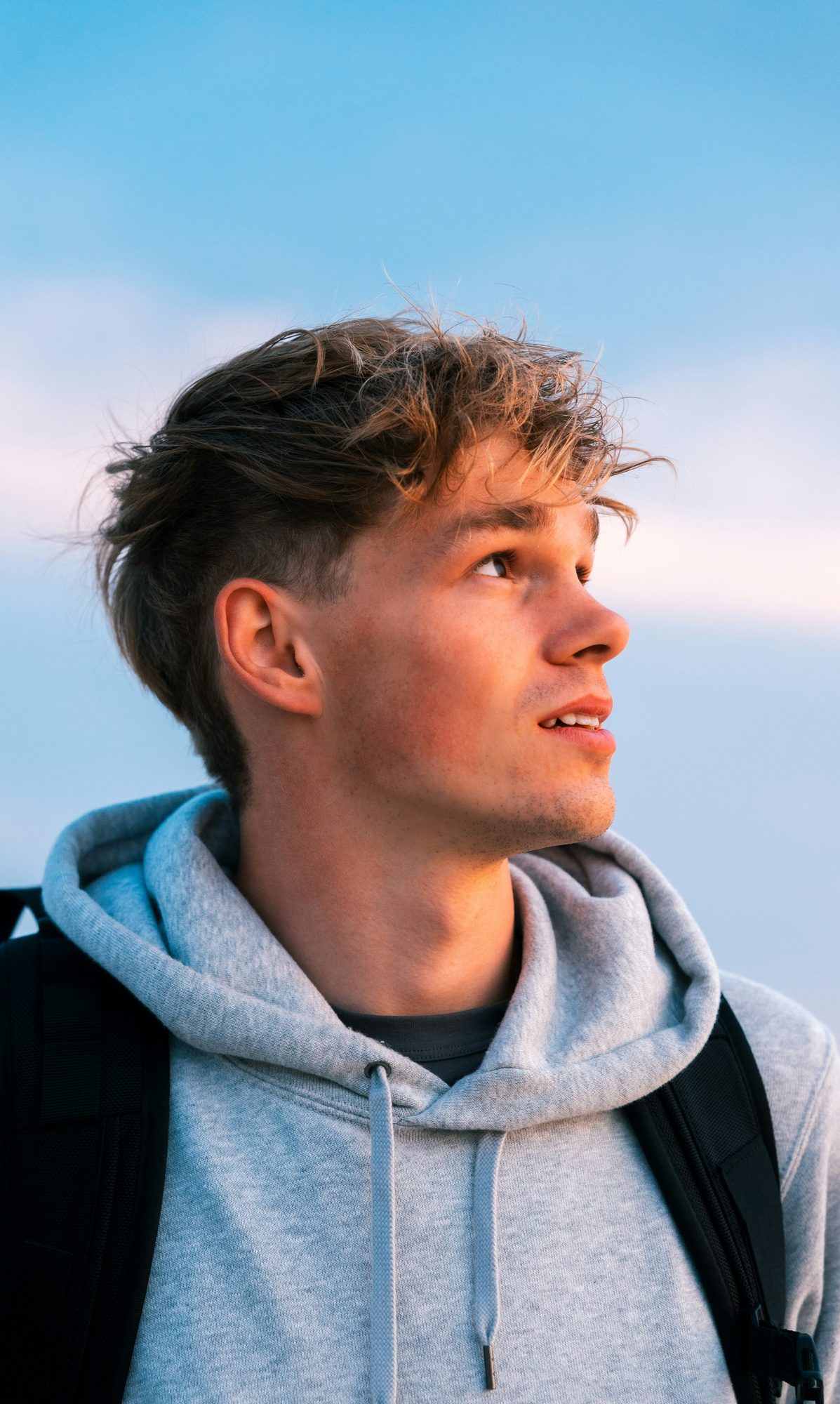 A person wearing a plain heavyweight hoodie outdoors.